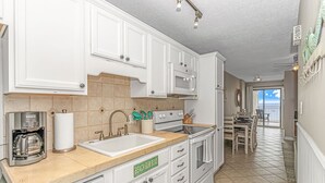 A modern kitchen with white cabinets, a coffee maker, a sink, and a stove.