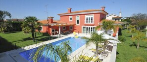 A two-story house with a swimming pool, surrounded by a well-maintained lawn and palm trees. - Moradia Marinhas - Five Bedroom Villa, Sleeps 10 (Fão)