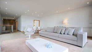 A modern living room with a white sofa, a glass coffee table, and a dining area in the background. - Villa Senande - Five Bedroom Villa, Sleeps 10 (Âncora)