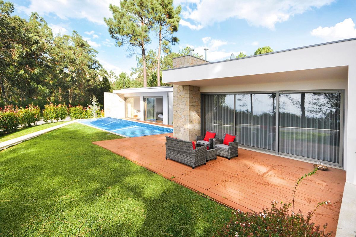 A modern house with a pool, outdoor seating, and a well-maintained lawn.