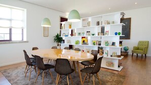 Ein modernes Wohnzimmer mit einem runden Esstisch, vier Stühlen, einem Bücherregal und einem grünen Sessel.