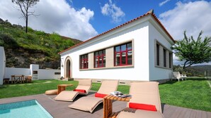 Eine moderne Villa mit Swimmingpool, Liegestühlen und einer Terrasse.