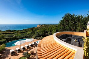 A curved outdoor seating area with a pool and umbrellas, overlooking a coastal landscape. - Villa Balei - Four Bedroom Villa, Sleeps 8 (Praia do Carvoeiro)