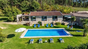 Ein modernes Gebäude mit Schwimmbad, umgeben von gepflegten Rasenflächen und Bäumen.