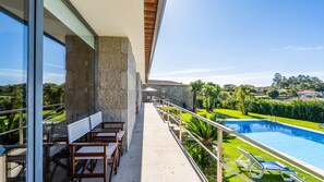 A balcony with a pool, outdoor seating, and a view of the surrounding landscape.