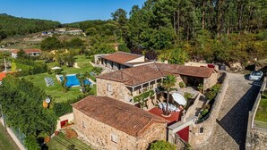Eine Steinvilla mit Swimmingpool, Sitzgelegenheiten im Freien und Blick auf die umliegende Landschaft.