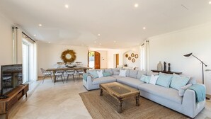 A spacious living room with a large L-shaped sofa, a coffee table, and a dining area with a table and chairs. - Villa Catao - Four Bedroom Villa, Sleeps 8 (Almansil)