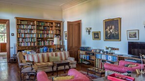 A spacious living room with a large bookshelf, a television, and a comfortable seating area. - Villa Quinta Santa Luzia (Funchal)