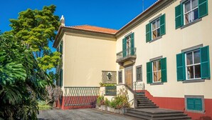 A two-story building with a red-tiled roof, green shutters, and a staircase leading to the upper floor. - Villa Quinta Santa Luzia (Funchal)