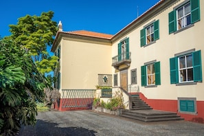 A two-story building with a red-tiled roof, green shutters, and a staircase leading to the upper floor. - Villa Quinta Santa Luzia (Funchal)