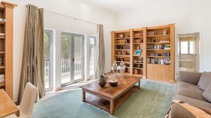 Un salón espacioso con una mesa de centro de madera, un sofá y una estantería llena de libros y objetos decorativos.