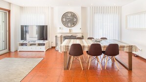 Un espace repas comprenant une table, des chaises, une horloge et un téléviseur.