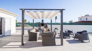 Une terrasse sur le toit, aménagée avec des meubles en osier, une pergola et un panier de basket.