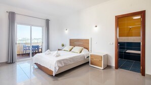 A modern bedroom with a bed, bedside table, and a view of the outdoors. - Villa Botela - Three Bedroom Villa, Sleeps 6 (Lagoa)