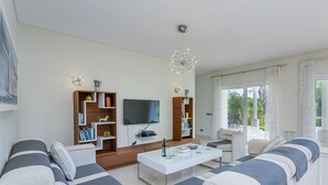 A modern living room with a sofa set, a coffee table, a TV, and built-in shelving.