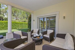 Relax in style with a seating area surrounded by lush gardens and a glass door.