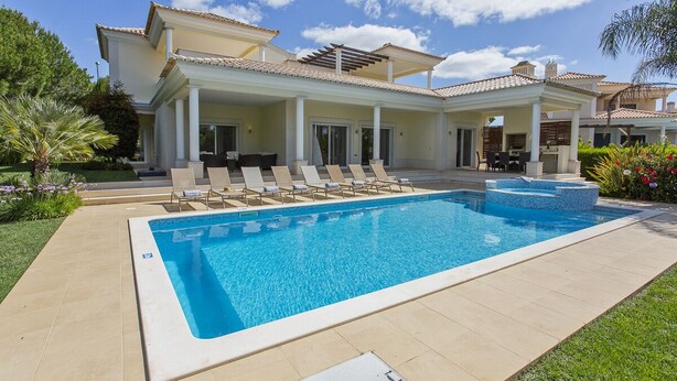 A large swimming pool with lounge chairs and a covered patio area.