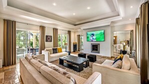 A spacious living room with a large flat-screen TV, a fireplace, and a view of the outdoors. - Villa Lella - Five Bedroom Villa, Sleeps 10 (Almansil)