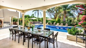 An outdoor dining area with a pool and lush greenery. - Villa Lella - Five Bedroom Villa, Sleeps 10 (Almansil)