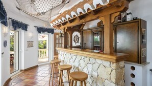 Una cocina con encimera de piedra, taburetes de madera y una hamaca colgante.
