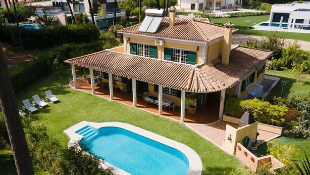 Une maison à deux étages avec une piscine, un patio couvert et une pelouse bien entretenue.