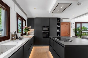 Een moderne keuken met een centraal eiland, inbouwapparatuur en uitzicht op de omgeving.