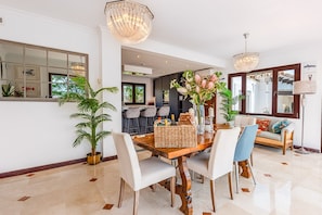 A dining area with a wooden table, white chairs, and a chandelier.