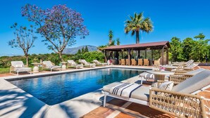 Un espace piscine avec des chaises longues et une pergola.