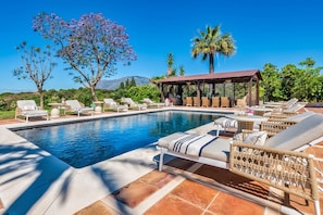Ein Poolbereich mit Liegestühlen und einer Pergola.