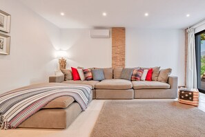 A modern living room with a sectional sofa, a patterned throw blanket, and a small side table. - Villa Lola - Five Bedroom Villa, Sleeps 10 (Estepona)