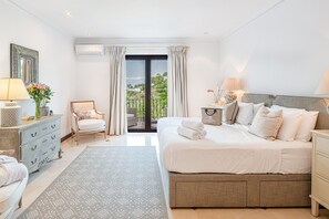 A hotel room with a large bed, a chair, a dresser, and a view of the outdoors.