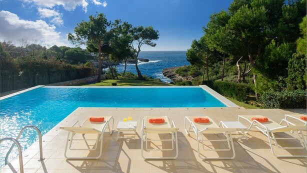 Une piscine avec des chaises longues et vue sur la mer.