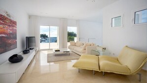 Un salon moderne avec un canapé, une table basse et un téléviseur posé sur un meuble blanc.