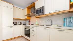 Une cuisine moderne avec des armoires blanches, un four à micro-ondes en acier inoxydable et un four encastré.