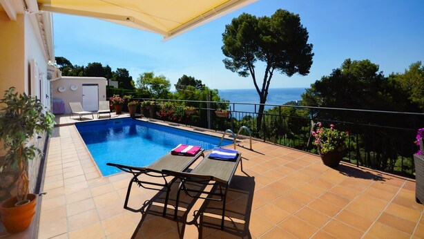 A poolside area with a view of the sea, a table with chairs, and potted plants. - Villa Petunies - Three Bedroom Villa, Sleeps 6 (Begur)