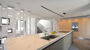 A modern kitchen with a marble countertop, a built-in sink, and wooden cabinetry. - Villa Falguerines - Six Bedroom Villa, Sleeps 12 (Begur)
