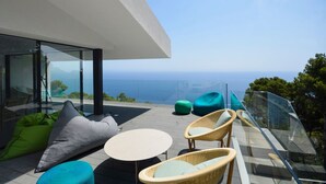 A modern outdoor seating area with wicker furniture and green cushions, overlooking a scenic ocean view. - Villa Falguerines - Six Bedroom Villa, Sleeps 12 (Begur)