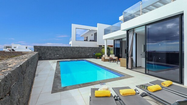 A modern villa with a swimming pool, outdoor seating, and a glass-enclosed balcony. - Villa Bernialiss - Three Bedroom Villa, Sleeps 6 (Puerto del Carmen)