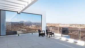 A modern interior with a large glass window offering a panoramic view of a desert landscape. - Villa Bernialiss - Three Bedroom Villa, Sleeps 6 (Puerto del Carmen)