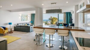 A modern kitchen with a bar area, a dining table, and a view of the ocean. - Villa Canwell - Four Bedroom Villa, Sleeps 8 (Puerto del Carmen)
