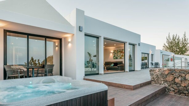 A modern house with a hot tub, outdoor seating, and a stone wall. - Villa Canwell - Four Bedroom Villa, Sleeps 8 (Puerto del Carmen)