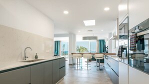 A modern kitchen with a central island, bar stools, and a view to the outside. - Villa Canwell - Four Bedroom Villa, Sleeps 8 (Puerto del Carmen)