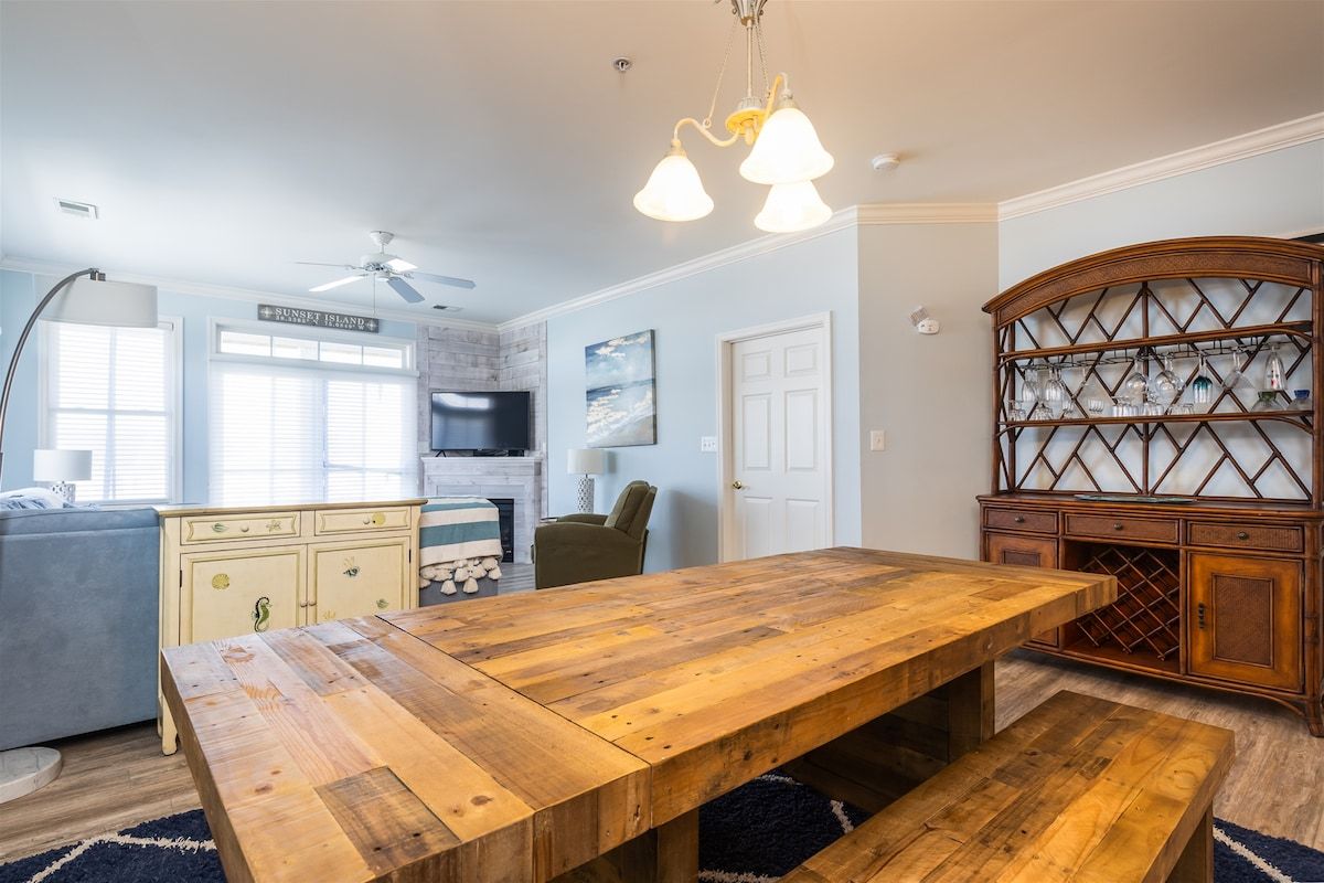Une cuisine spacieuse avec une table à manger en bois, un meuble à vin intégré et un ventilateur de plafond.