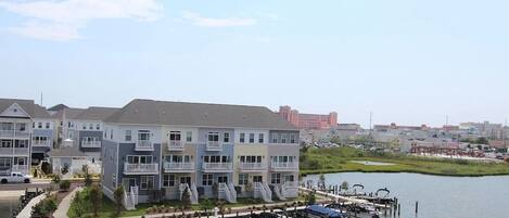A waterfront residential building with multiple balconies, a dock with boats, and a marina in the background.