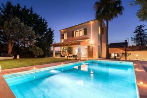 Ein zweistöckiges Haus mit Swimmingpool, Gartenmöbeln und einem gepflegten Rasen.