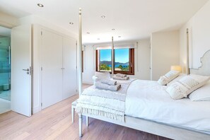 Une chambre à coucher avec un lit, une table de chevet, une fenêtre donnant sur un paysage agréable et une porte.