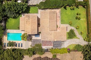 Un grand bâtiment comprenant de nombreuses pièces, une piscine et des jardins bien entretenus.