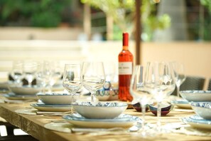 Une table à manger dressée avec de l’assiette bleue et blanche, des verres transparents et une bouteille de vin rouge.