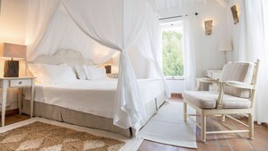 A bedroom with a canopy bed, a chair, a nightstand, and a lamp. - El Cortijo - Seven Bedroom Villa, Sleeps 12 (Ronda)