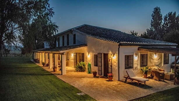 A two-story house with a patio area, outdoor seating, and a well-maintained lawn. - El Cortijo - Seven Bedroom Villa, Sleeps 12 (Ronda)